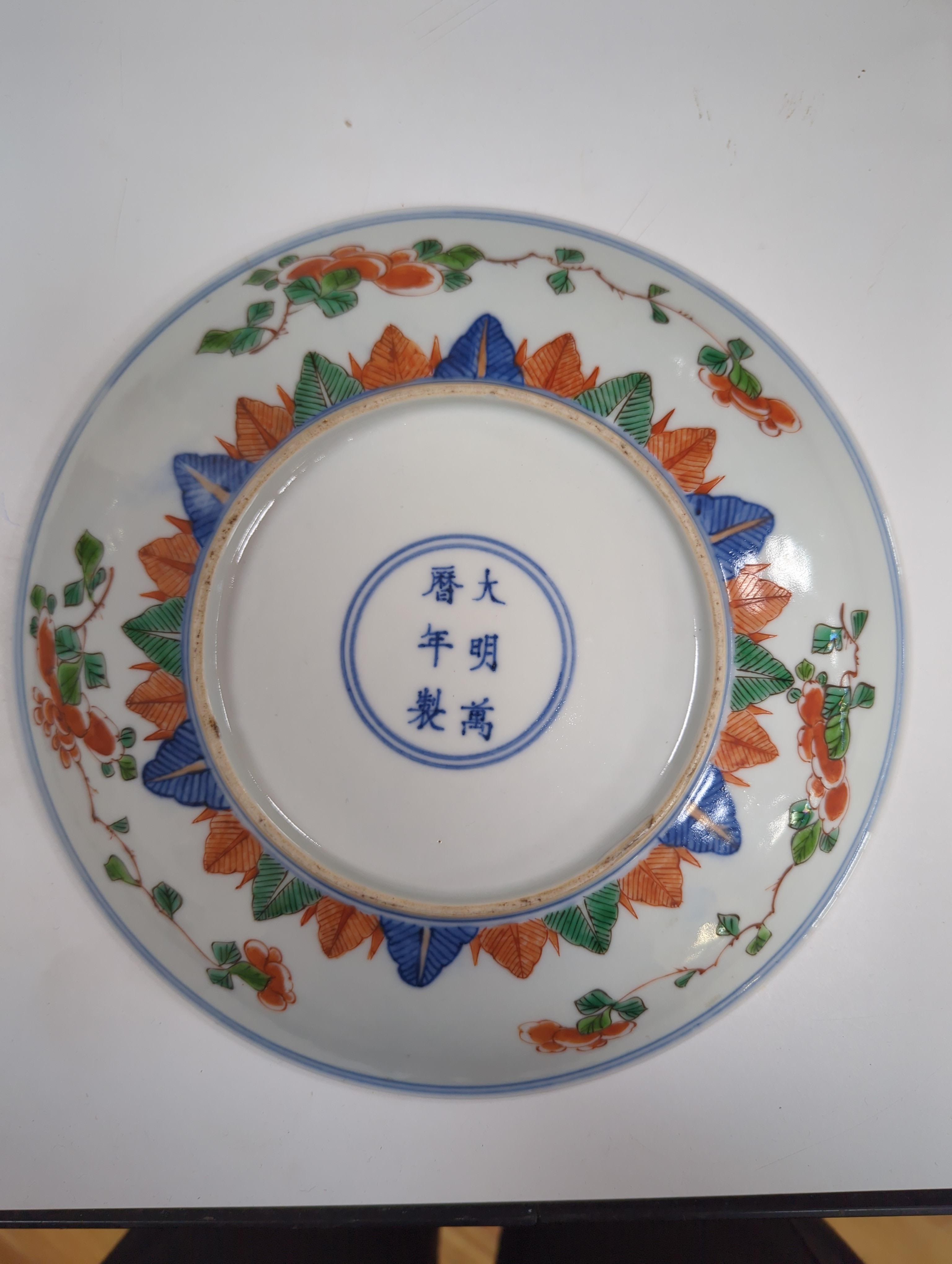 An 18th century Chinese famille rose bowl and a group of five Chinese wucai plates, each decorated with fruit, the bowl 23cm in diameter